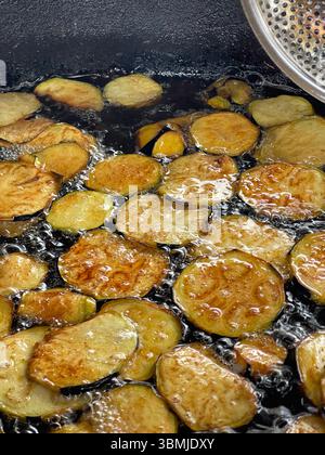 Frire des tranches d'aubergine dans l'huile, cuisine de rue populaire. Banque D'Images