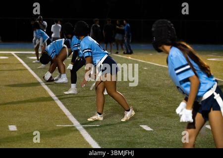 Les joueurs de football de drapeau offensif s'alignent sur la ligne de scrimmage et se préparent à claquer le ballon vu dans les uniformes bleu blanc et noir Banque D'Images