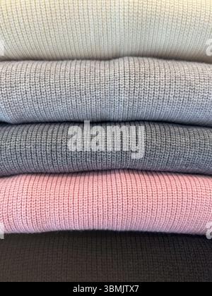 Gros plan de vêtements soigneusement pliés, montrant uniquement des rayures visibles dans une gamme de couleurs harmonisées. Probablement des pulls ou des tricots, créant une texture douce Banque D'Images