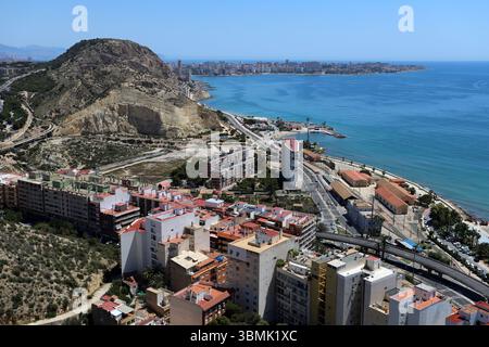 Vue sur la côte de la plage de Postiguet à Alicante avec mer bleue, hôtels modernes, palmiers et promenade en bord de mer. Banque D'Images