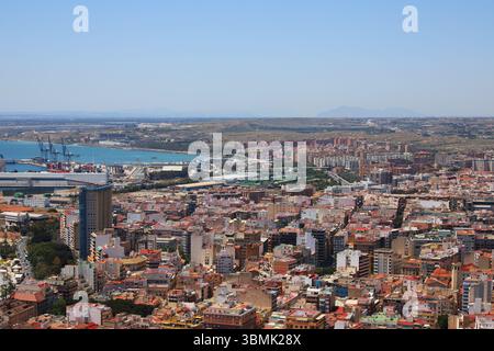 Vue sur la côte de la plage de Postiguet à Alicante avec mer bleue, hôtels modernes, palmiers et promenade en bord de mer. Banque D'Images