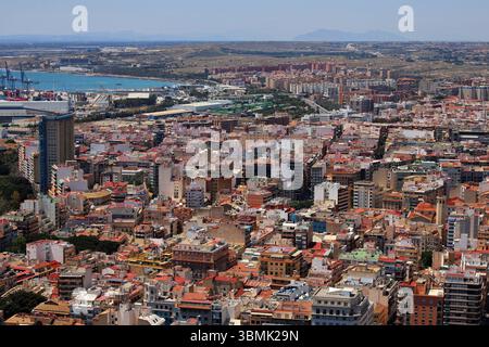 Vue sur la côte de la plage de Postiguet à Alicante avec mer bleue, hôtels modernes, palmiers et promenade en bord de mer. Banque D'Images