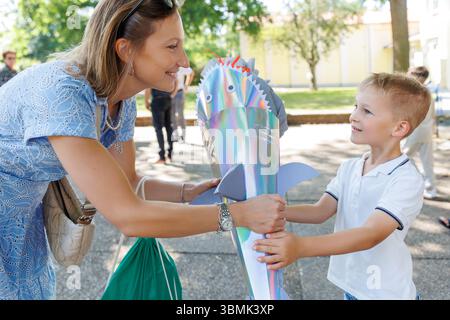 Maman heureuse donnant le fils souriant garçon tient Schultuete coloré en forme de requin rempli de cadeaux son premier jour d'école Allemagne. Cône brillant avec ailettes Banque D'Images