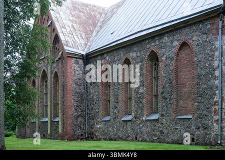Église historique en pierre avec fenêtres de style gothique et détails en briques dans la campagne estonienne, Äksi Banque D'Images
