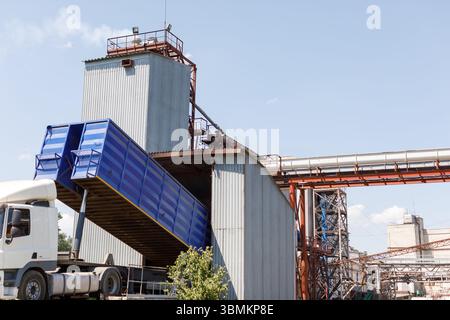 Camion déchargeant le grain à l'installation d'ascenseur avec silos et convoyeurs modernes dans la logistique agricole et l'industrie de stockage Banque D'Images