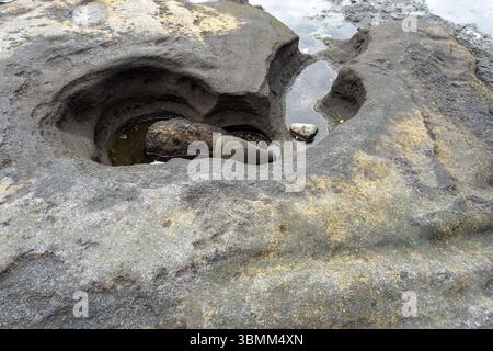 Rocher avec un trou dedans et une petite masse d'eau dans le trou. Le trou a la forme d'un coeur Banque D'Images
