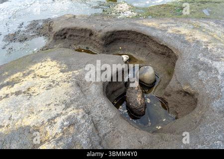 Rocher avec un trou dedans et une petite masse d'eau dans le trou. Le trou a la forme d'un coeur Banque D'Images