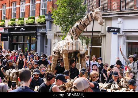 Londres, Royaume-Uni. 27 juin 2025. Les marionnettistes avec leur troupeau d'animaux marchent de Sevel Dials à Covent Garden en passant par Soho et le Strand jusqu'à Somerset House cet après-midi, interagissant avec le public. LES TROUPEAUX sont l'art public et l'action climatique. D’avril à août 2025, les animaux marionnettes grandeur nature parcourent un itinéraire de 20 000 km entre le bassin du Congo et le cercle arctique, symbolisant leur fuite de la catastrophe climatique avec des arrêts dans de nombreuses villes et pays, à Londres du 27 au 29 juillet. Crédit : Imageplotter/Alamy Live News Banque D'Images