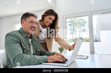 Heureux couple de vieillesse aîné utilisant la technologie d'ordinateur portable à la maison. Banque D'Images