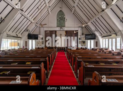Un tapis rouge vif mène à l'autel de la cathédrale Marys de Kuala Lumpur. De hautes poutres en bois et des vitraux créent une atmosphère paisible pour les visiteurs Banque D'Images