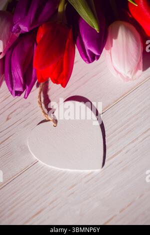 Design plat représentant des tulipes blanches rouges violettes sur bois avec ornement en forme de coeur et boucle de ficelle Banque D'Images