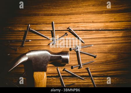 Graphique plat montrant un marteau à griffes en métal avec manche en bois reposant sur une planche parsemée de clous Banque D'Images