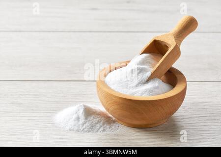 bicarbonate de soude dans une pelle en bois et un bol sur une table en bois clair. Banque D'Images