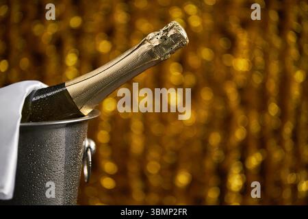 Bouteille complète de champagne dans un seau avec de la glace sur fond de bokeh de noël. Thème de célébration avec du champagne nature morte Banque D'Images