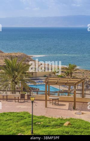 Piscine de l'hôtel sur les rives de la mer morte en Jordanie. Dans l'eau de mer pure cristaux de sel visibles. De l'autre côté de la zone visible d'Israël Banque D'Images