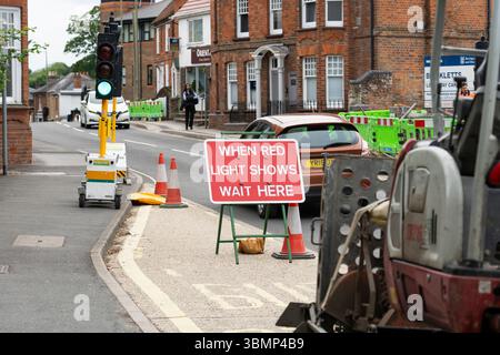 Lorsque le feu rouge s'allume, attendez ici le panneau d'instructions pour la circulation sur Winchester Road en raison de travaux routiers avec feux de circulation temporaires et cônes. Basingstoke, Royaume-Uni Banque D'Images