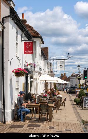 Les gens buvant et mangeant un jour d'été assis devant le pub Red Lion et Bel & the Dragon (George Hotel) sur Odiham High Street, Royaume-Uni Banque D'Images