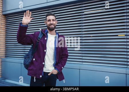Portrait de demi-longueur beau barbu habillé dans des vêtements à la mode dans la rue alors que l'article contre la paroi arrière-plan avec salon pour la publicité Banque D'Images