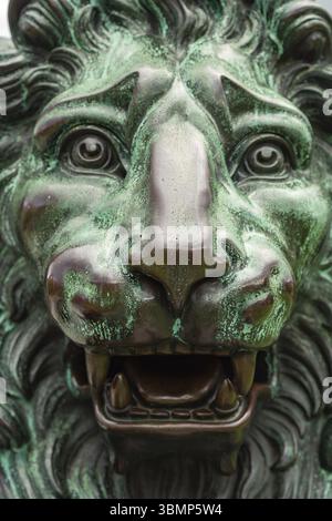 Statue de lion vieillie. Gros plan de la tête d'une sculpture en bronze d'un lion. Grande sculpture de statue de lion en bronze dans un cadre extérieur Banque D'Images