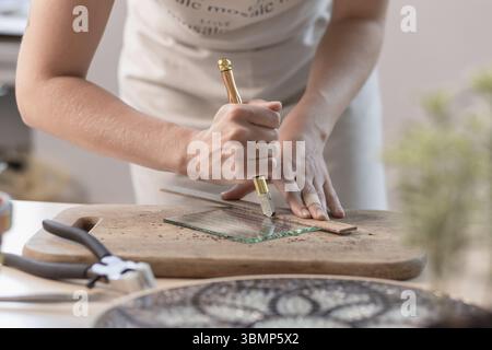 Feuilles à découper l'artiste du vitrail en petits carrés de mosaïque. Close-up. Atelier. Lieu de travail Banque D'Images