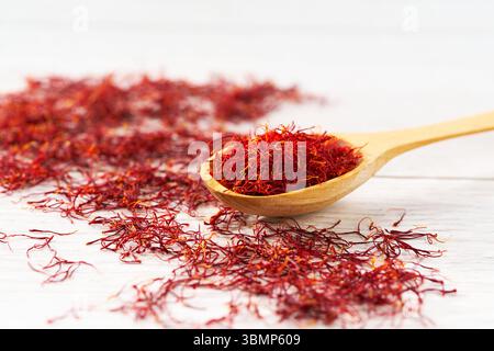 stigmates safran dans une cuillère en bois sur une table blanche, mise au point sélective. Banque D'Images