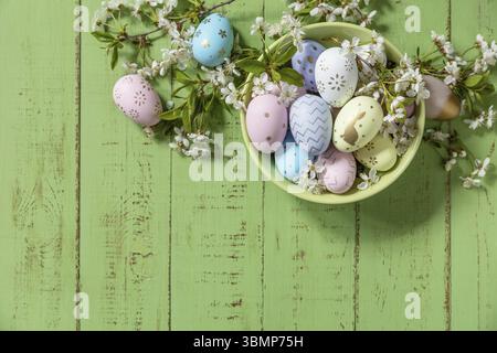Composition de Pâques. Branches d'un pommier en fleur, œufs de Pâques faits à la main colorés sur une table en bois rustique pastel. Joyeuses Pâques. Vue de Banque D'Images
