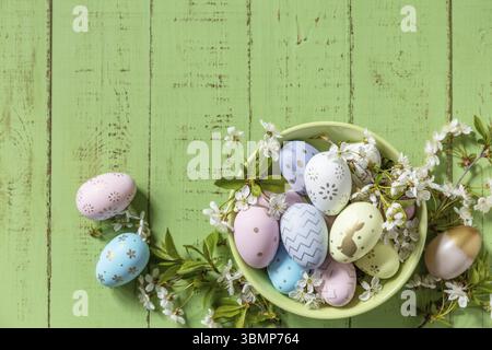Composition de Pâques. Branches d'un pommier en fleur, œufs de Pâques faits à la main colorés sur une table en bois rustique pastel. Joyeuses Pâques. Vue de Banque D'Images