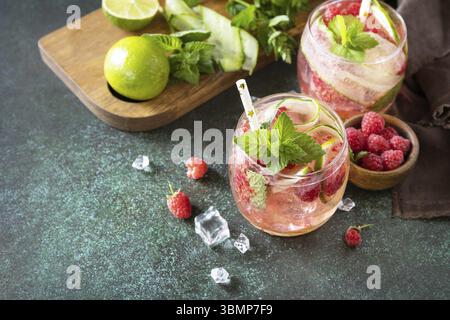 Boissons non alcoolisées, boissons saines, eau amincissante. Des boissons détox rafraîchissantes à base de framboises biologiques, de concombres, de chaux et de feuilles de menthe sur une table en pierre Banque D'Images