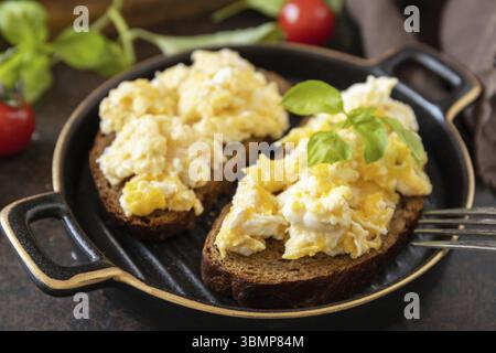 Oeufs brouillés sur pain de grains entiers. Petit-déjeuner maison ou brunch - œufs brouillés Banque D'Images