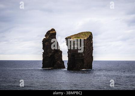 Deux îlots rocheux se dressent dans l'océan Atlantique sous un ciel nuageux, créant un paysage marin spectaculaire près de Praia dos Mosteiros, aux Açores Banque D'Images
