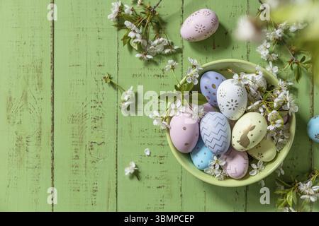 Composition de Pâques. Branches d'un pommier en fleur, œufs de Pâques faits à la main colorés sur une table en bois rustique pastel. Joyeuses Pâques. Vue de Banque D'Images