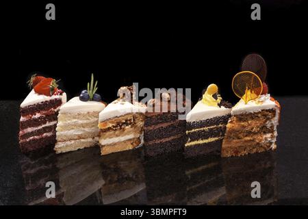 Un assortiment de gros morceaux de gâteaux différents : chocolat, framboises, fraises, noix, les bleuets. Des gâteaux sont décorées avec des baies, d'écrous. Morceaux de c Banque D'Images