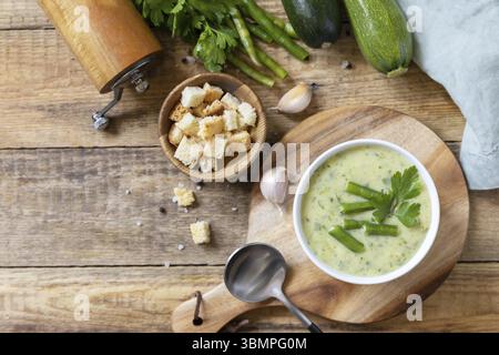 Purée de légumes verts à la soupe végétalienne. Bol de soupe à la crème de haricots verts et de courgettes sur une table rustique. Régime alimentaire sain faible carb. Vue de dessus. Copier l'espace Banque D'Images