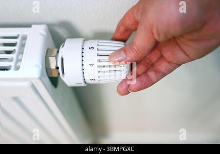 La personne règle la température du radiateur Banque D'Images