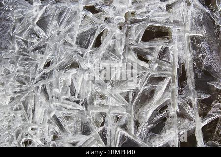 Cristaux de glace formés sur le bord de l'eau courante avec un fond noir Banque D'Images