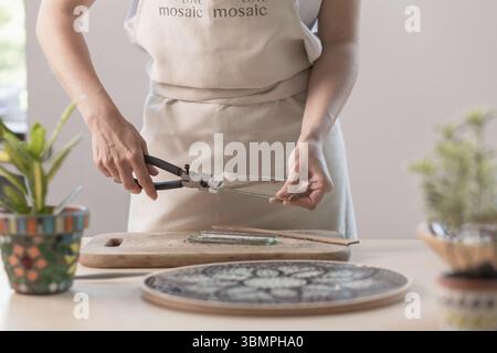 Feuilles à découper l'artiste du vitrail en petits carrés de mosaïque. Close-up. Atelier. Lieu de travail Banque D'Images