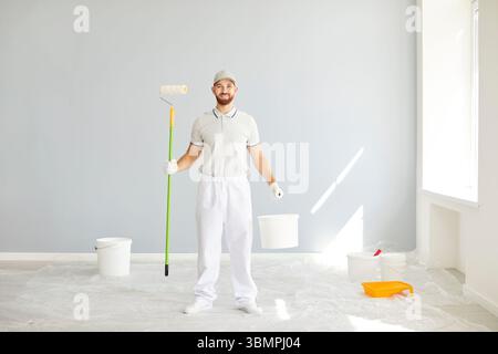 Happy Painter tenant le rouleau et le seau pendant la rénovation de la maison Banque D'Images