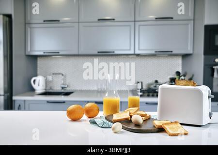 Table pour le petit déjeuner servi avec pain grillé et jus d'orange, sur fond flou. Copy space Banque D'Images