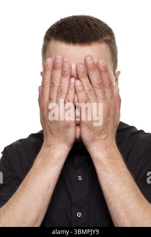 Huebscher junger Mann im schwarzen Hemd schneidet Grimassen, waehrend er isoliert auf einem weissen Hintergrund steht Banque D'Images