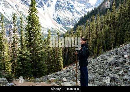 Randonneur féminin debout sur un sentier rocheux avec des montagnes enneigées en arrière-plan Banque D'Images