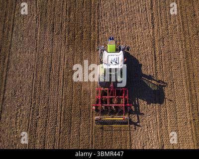 Vue aérienne d'un tracteur vert labourant un champ laissant des chenilles sur le champ Banque D'Images