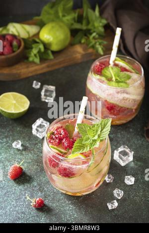 Boissons non alcoolisées, boissons saines, eau amincissante. Des boissons détox rafraîchissantes à base de framboises biologiques, de concombres, de chaux et de feuilles de menthe sur une table en pierre Banque D'Images