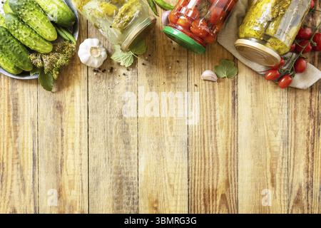 Concombres marinés salés et tomates conservés en conserve dans un bocal en verre. Économie domestique, préservation des récoltes d'automne. Aliments fermentés faits maison sains. Vie Banque D'Images