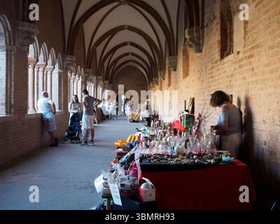 Alseno, Italie 22 juin 2025 touristes et vendeurs marchant et vendant des objets dans le cloître suggestif de l'abbaye de Chiaravalle della Colomba pendant Banque D'Images