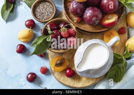 Ingrédients pour un smoothie sain. Lait et baies (framboise, cerise, prune, abricot) sur une table en pierre. Alimentation saine, alimentation crue et végétalien f Banque D'Images