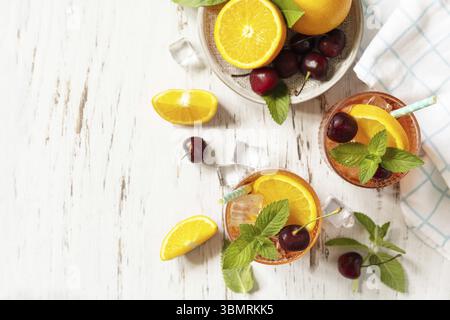 Boisson fraîche d'été. Boisson rafraîchissante glacée limonade de cola cerise orange ou cocktail mojito dans un verre sur une table en bois. Vue de dessus. Copier l'espace Banque D'Images