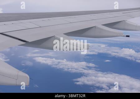 Vue en vol de l'aile d'avion et des moteurs d'avion au-dessus de ciel nuageux - voyage commercial et concept d'aviation Banque D'Images