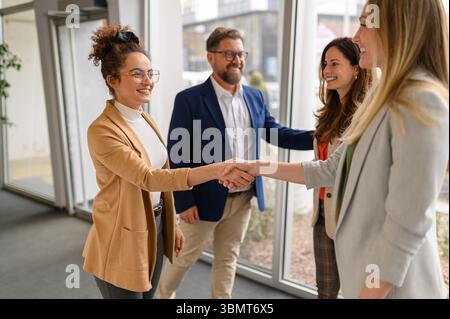 Équipe de professionnels échangeant des poignées de main et des salutations au bureau lors d'une réunion d'affaires ou d'une collaboration Banque D'Images