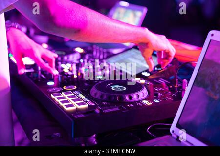 Console de musique DJ et ordinateurs portables aux couleurs vives de la lumière dans le fond sombre de boîte de nuit Banque D'Images