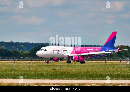 Memmingerberg, Bavière, Allemagne - 28 juin 2025 : un Airbus A320 exploité par les taxis Wizz Air est installé sur la piste de l'aéroport FMM de Memmingen. L'avion porte la superbe livrée rose et bleue de la compagnie aérienne ou low cost *** Ein Airbus A320 der Fluggesellschaft Wizz Air Rollt auf dem Rollfeld des Flughafens Memmingen FMM zur Startbahn. Der Jet trägt die auffällige rose-blaue Lackierung der Airline bzw Billigfluggesellschaft Banque D'Images